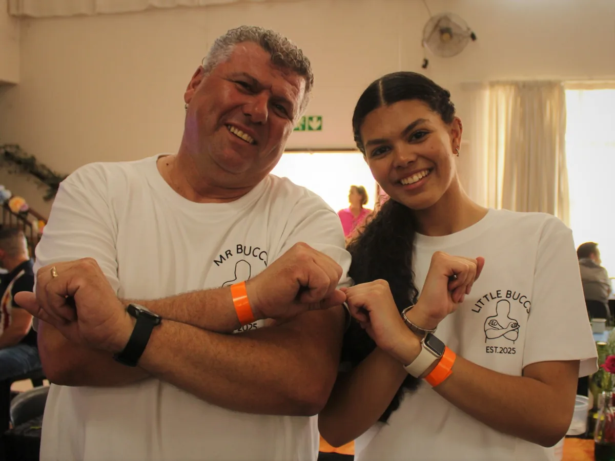 Mr Buccs and Little Buccs smiling in matching white T-shirts at a community event