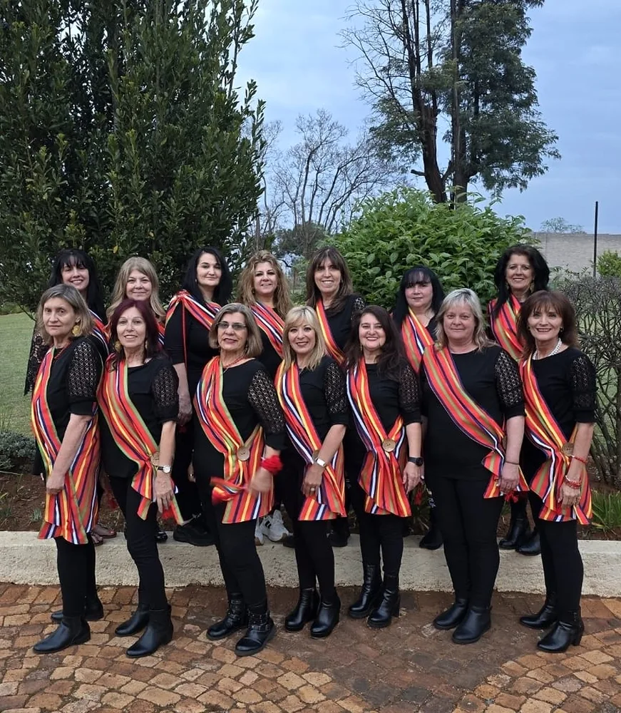 Members of the society outdoors in black outfits with striped sashes