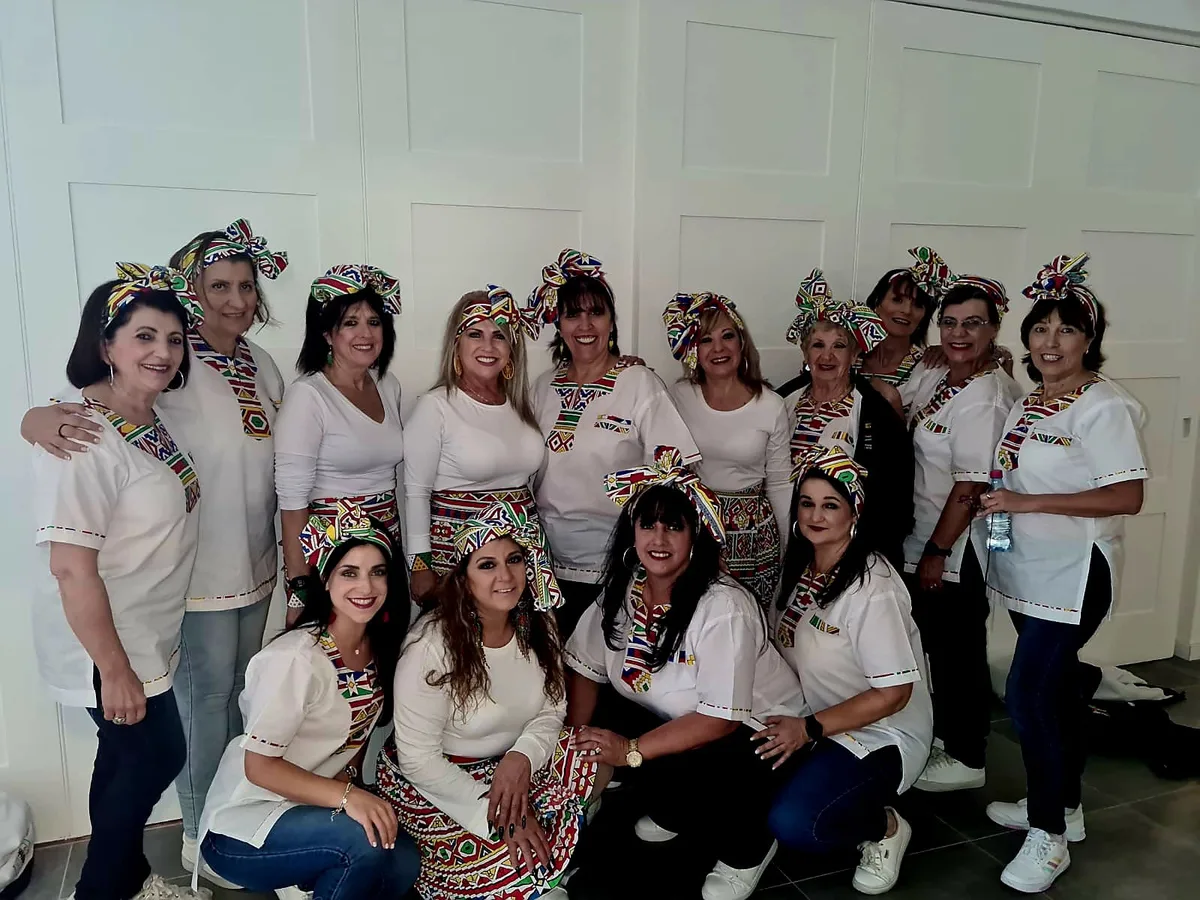 The troupe in white tops and patterned head wraps