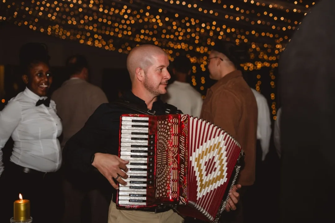 Ricardo playing the accordion among guests at an evening function