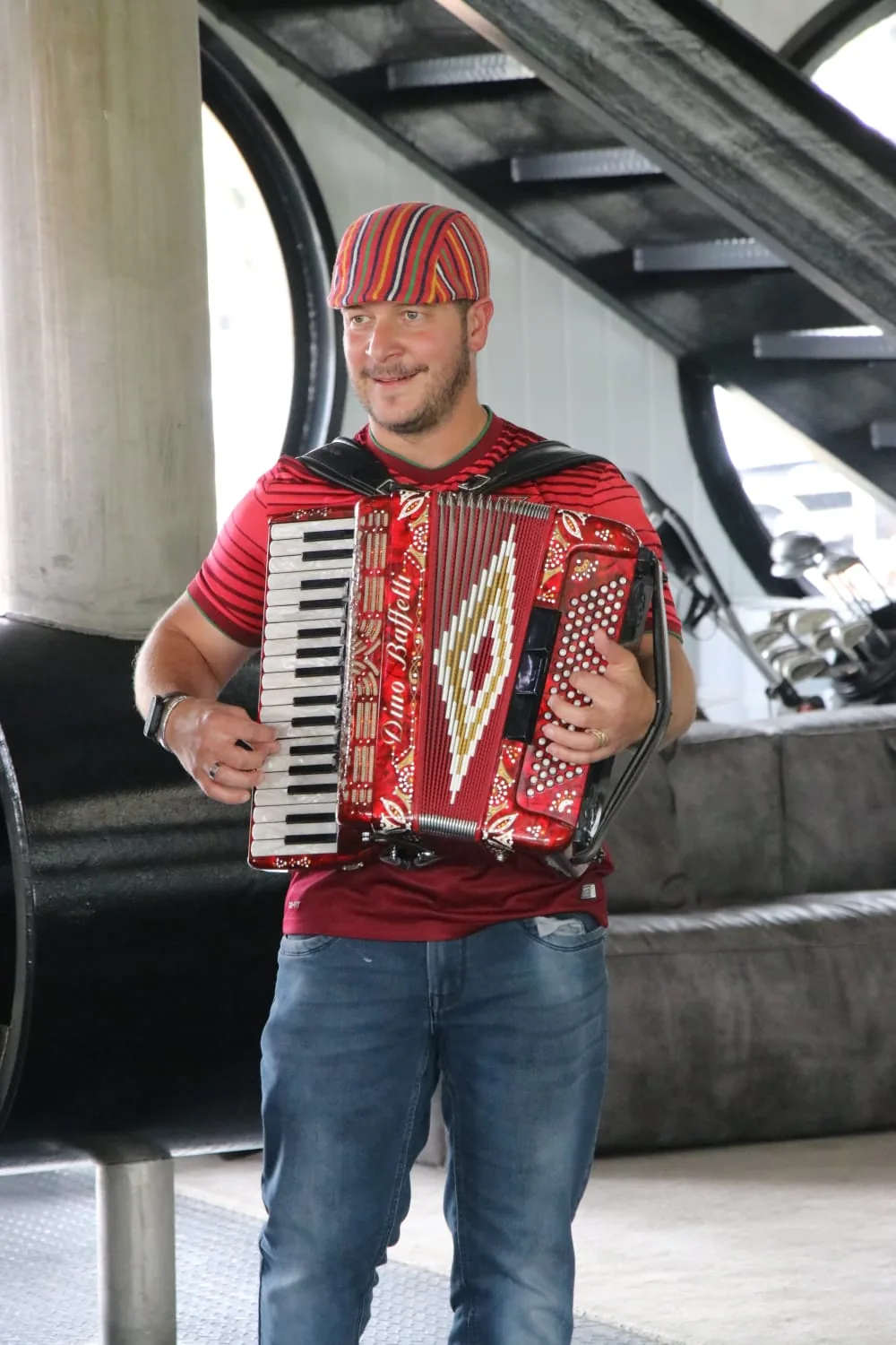 Ricardo da Conceição in a red Madeiran cap playing a red piano accordion